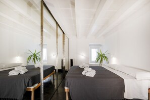 A hotel room with two beds, a large mirror, and potted plants.