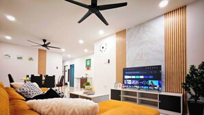Ein modernes Wohnzimmer mit einer Couch, einem Fernseher und einem Deckenventilator.
