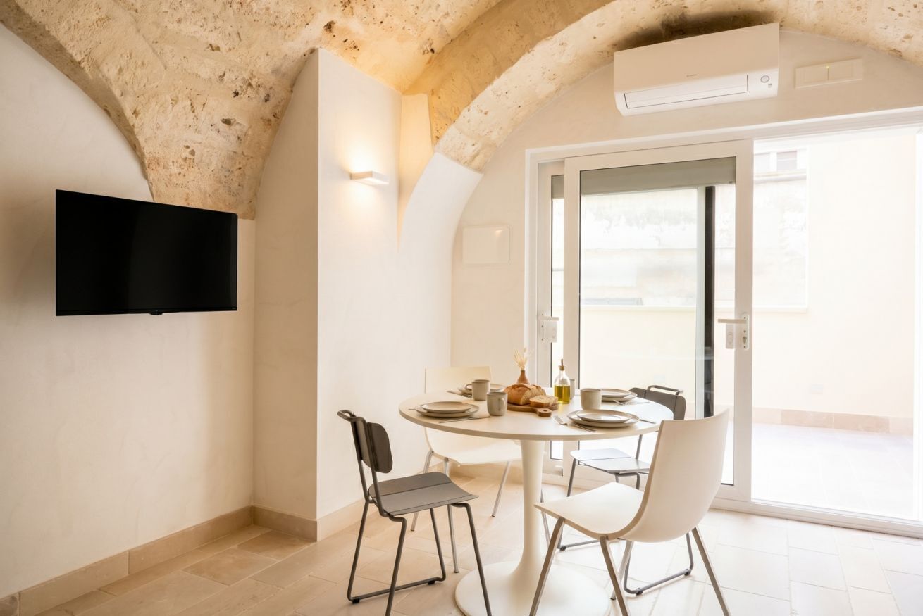 Un'area pranzo con un tavolo rotondo, sedie e una televisione montata a parete.