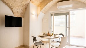 A dining area with a round table, chairs, and a television mounted on the wall.
