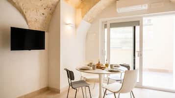Un'area pranzo con un tavolo rotondo, sedie e una televisione montata a parete.