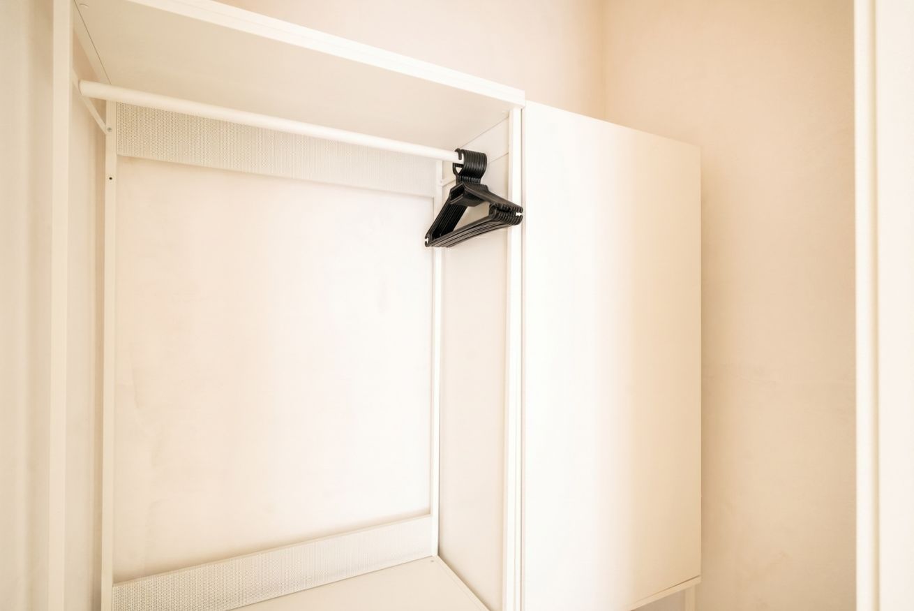 A white wardrobe with a hanging rod and a door.