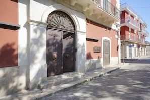 A building with a large, ornate entrance door, a small balcony, and a clear sky.