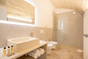 Ein modernes Badezimmer mit großem Waschbecken, Toilette und begehbarer Dusche.