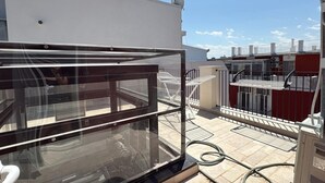 A rooftop terrace with a glass balustrade, outdoor furniture, and a view of adjacent buildings. - Palazzo della Torre 001 - Historical modern stay (Bari)