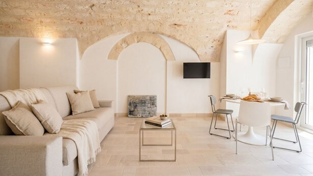A living room with a sofa, a coffee table, and a dining area with chairs and a table.