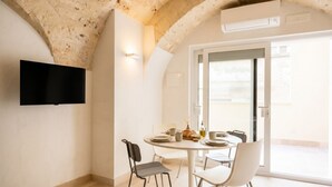 A dining area with a round table, chairs, and a television mounted on the wall. - Palazzo della Torre 001 - Historical modern stay (Bari)