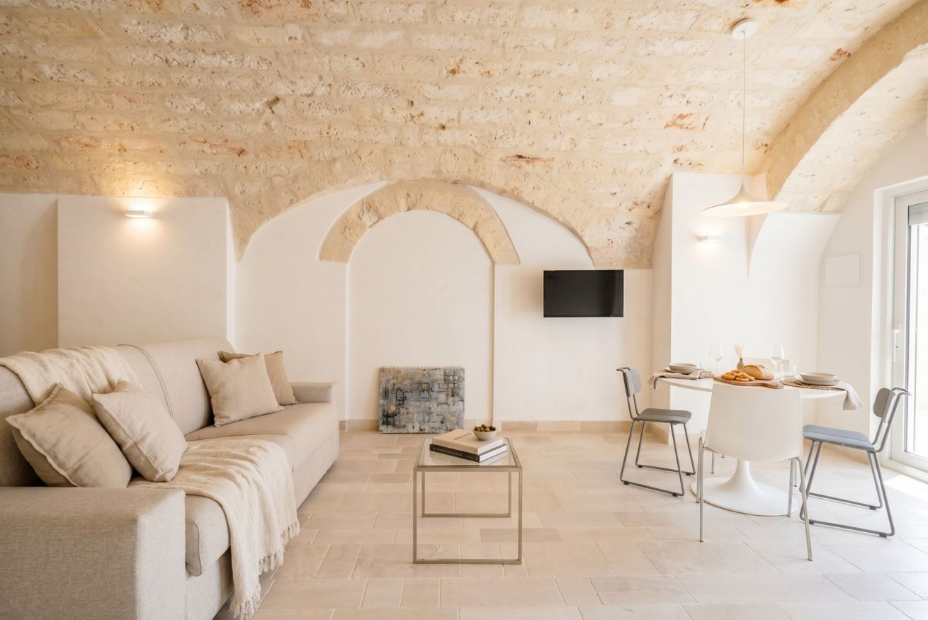 A living room with a sofa, a coffee table, and a dining area with chairs and a table.