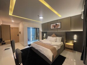 A modern bedroom with a bed, bedside table, and a sliding door leading to a bathroom. - Humble Citadel Hotel (Lagos)