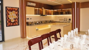 A modern hotel kitchen with a marble countertop, a central island, and a dining area set for a meal. - Humble Citadel Hotel (Lagos)