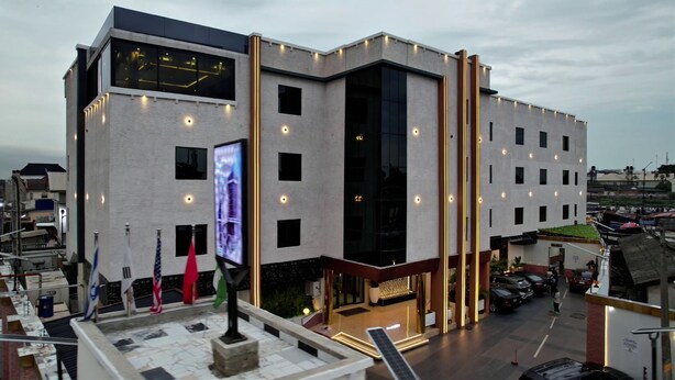 A modern hotel with a large glass facade, multiple balconies, and a rooftop terrace. - Humble Citadel Hotel (Lagos)