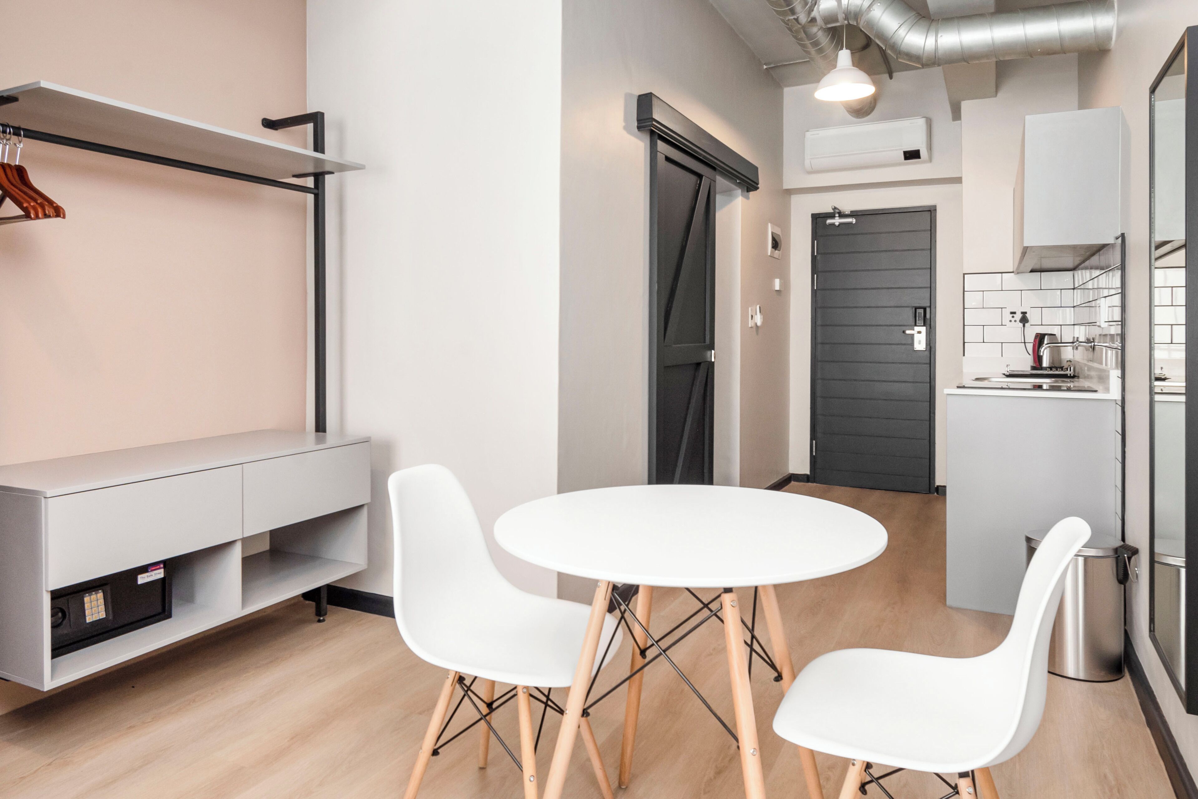Una cocina moderna con una mesa y sillas blancas, un horno empotrado y una puerta gris.