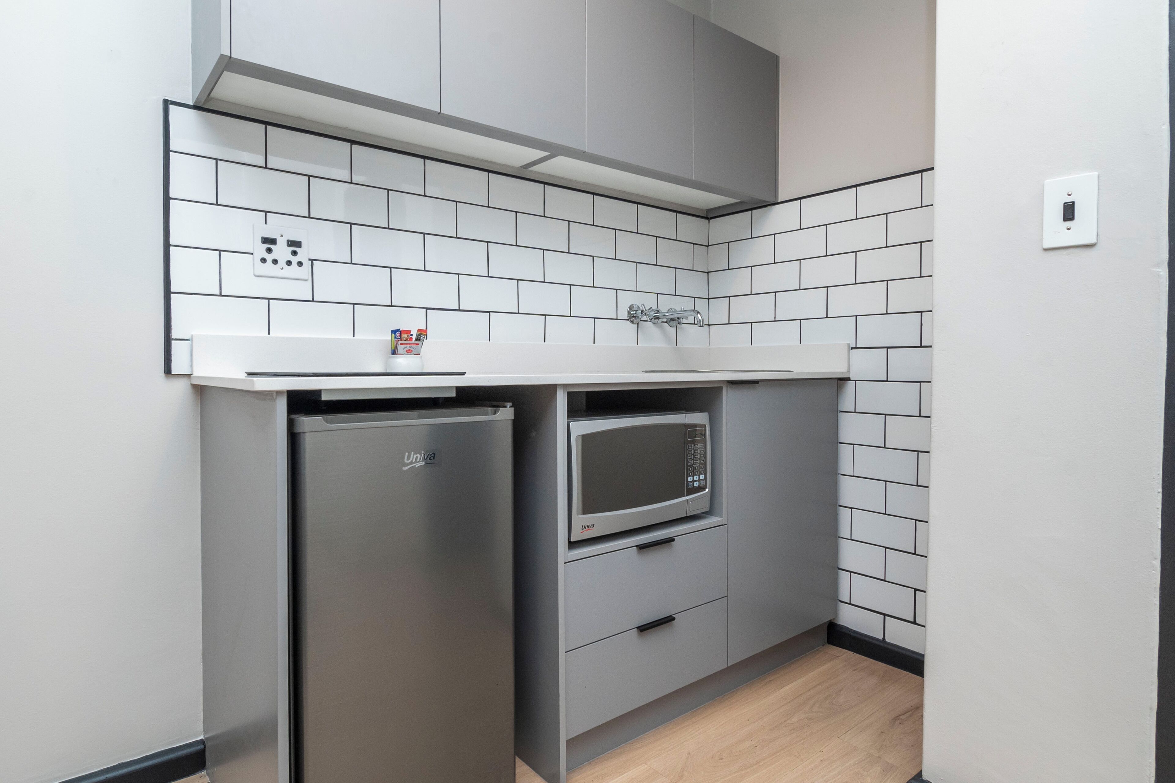 A compact kitchen with a built-in refrigerator, microwave, and a small countertop.