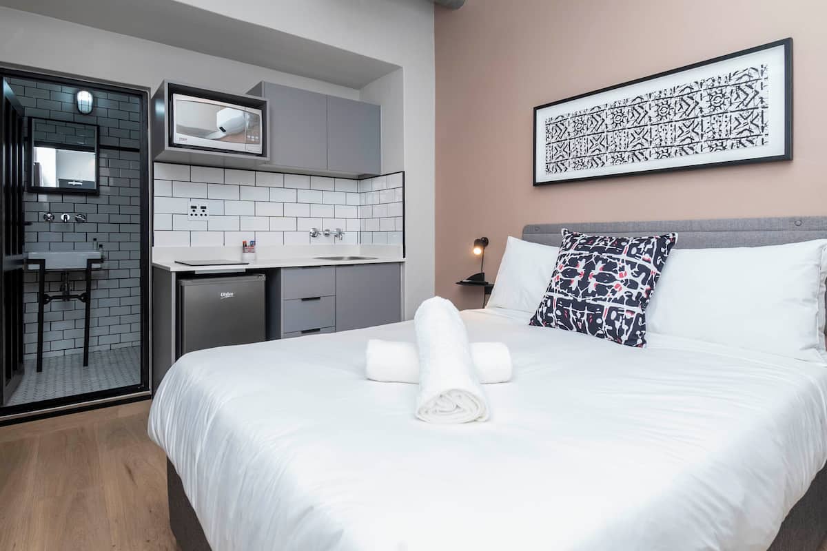 Una habitación de hotel moderna con cama, escritorio y kitchenette.