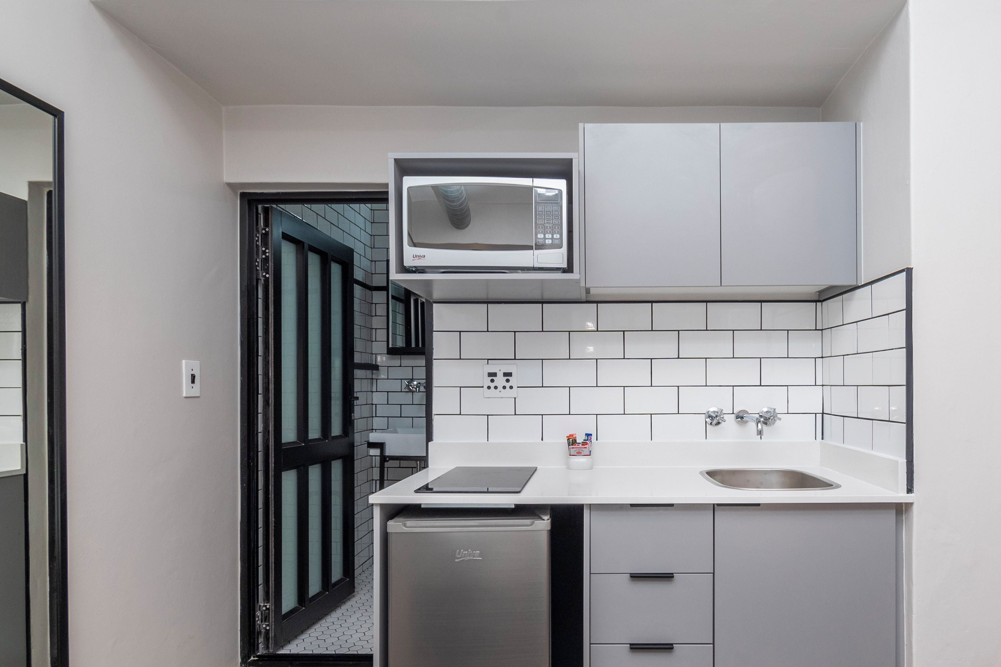 A compact kitchen with a microwave, dishwasher, and a small sink.