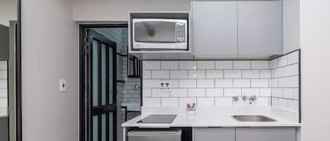 A compact kitchen with a microwave, dishwasher, and a small sink.