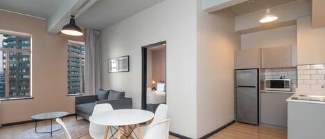 A modern apartment with a dining area, kitchen, and a view of the city.