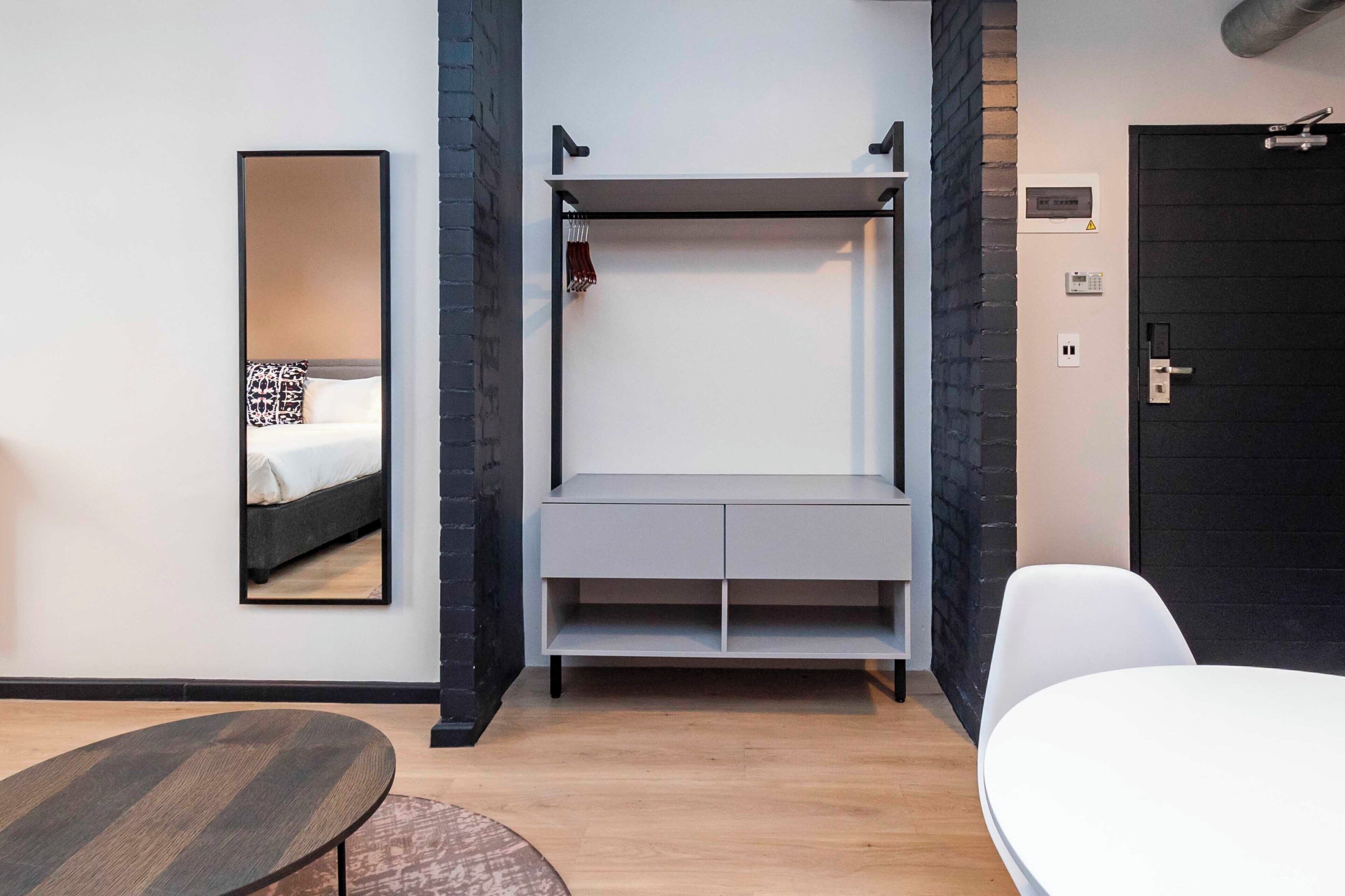 Et moderne hotelværelse med seng, skrivebord, stol og garderobeskab.