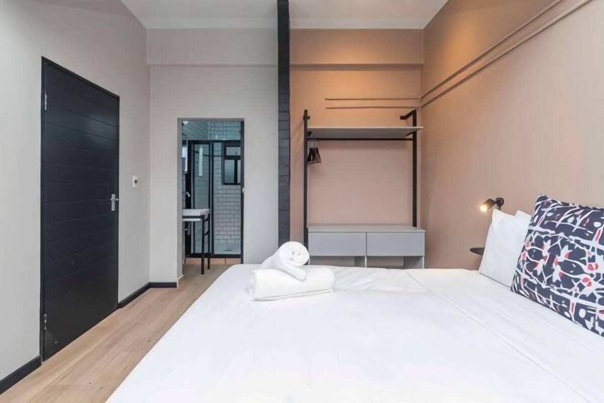 Una habitación de hotel moderna con cama, mesita de noche y armario.
