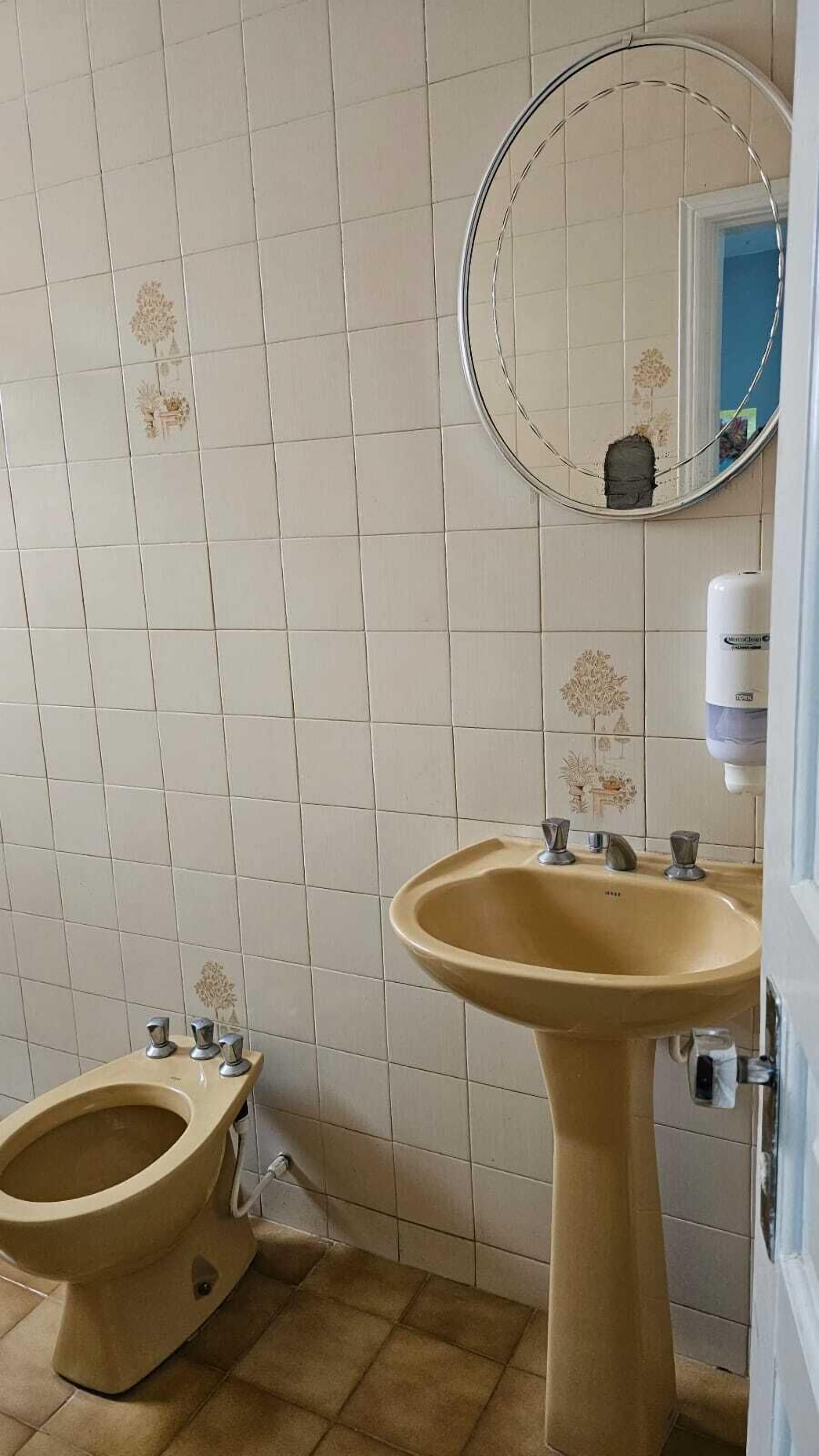 Un baño con inodoro, lavamanos y espejo.