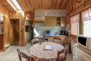 A wooden cabin interior with a kitchen, dining area, and a small living space.