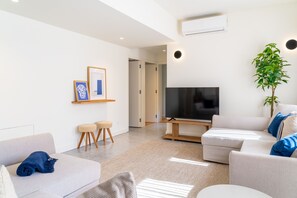 A modern living room with a flat-screen TV, two sofas, a coffee table, and a potted plant. - Feel Porto Tawny Townhouse (Porto)