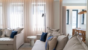 Un salon moderne comprenant un ensemble de canapés, une lampe sur pied et un coin repas avec des chaises et une table.