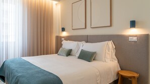 Une chambre d’hôtel avec un lit, une table de chevet, une lampe et une fenêtre avec des rideaux.