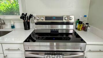 Una cocina con extractor de acero inoxidable, horno empotrado y microondas.