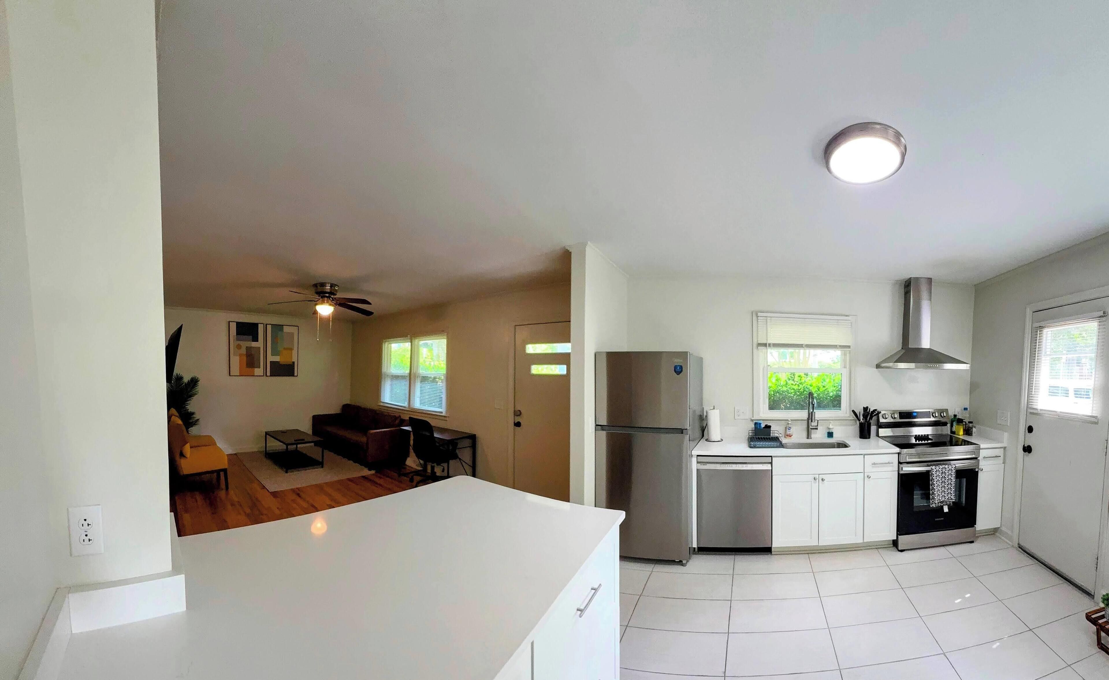 A modern kitchen with white cabinets, a stainless steel refrigerator, and a built-in oven.