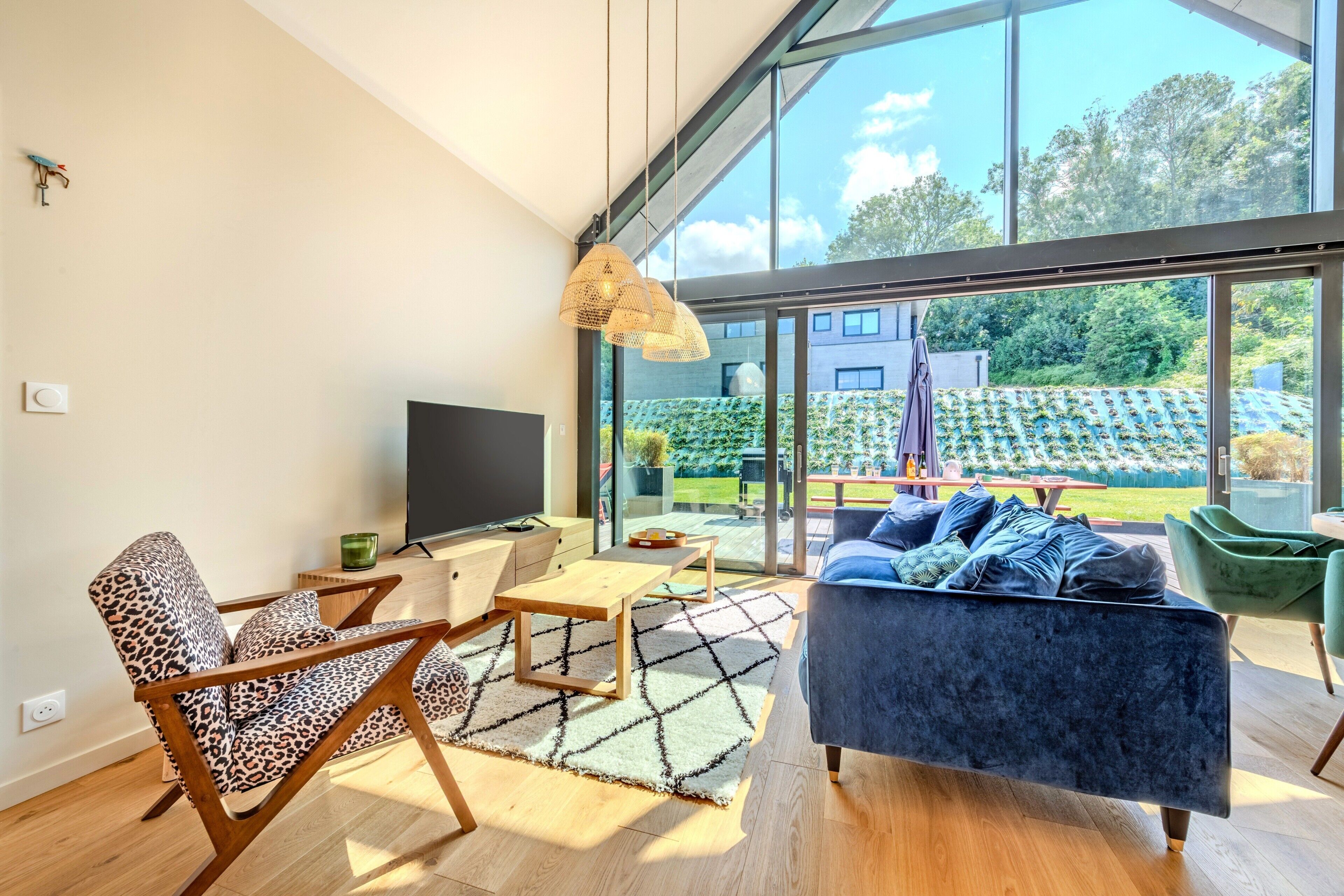Een moderne woonkamer met een groot raam, een bank, een salontafel en een televisie.