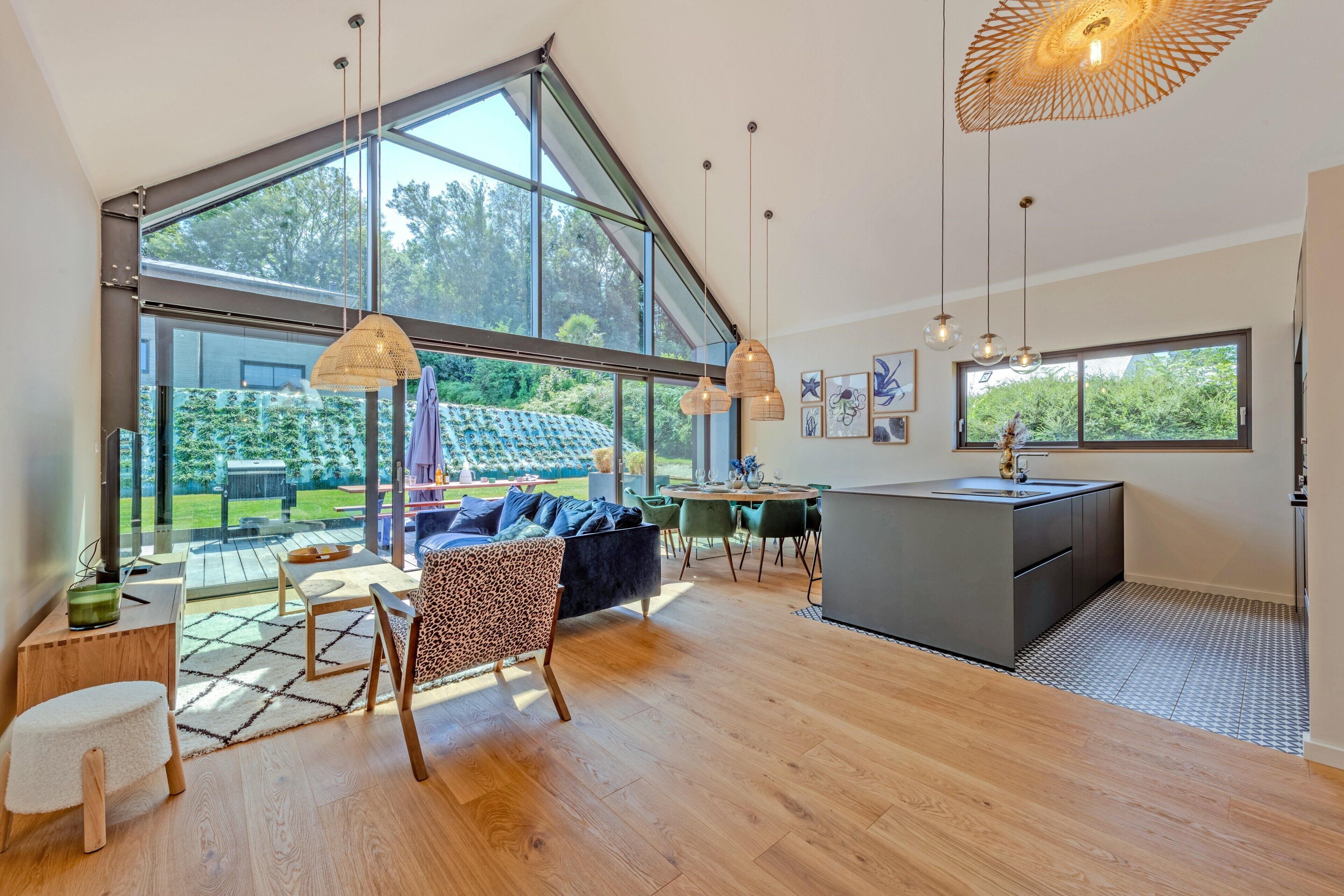 A spacious living area with large windows, a kitchen island, and a dining area with chairs and a table.