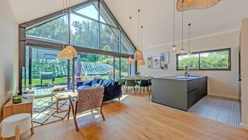 A spacious living area with large windows, a kitchen island, and a dining area with chairs and a table.