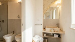 Une salle de bain moderne équipée d’un bidet, de toilettes et d’un meuble-lavabo avec un miroir.