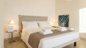 Une chambre d’hôtel avec un lit, deux tables de chevet, une lampe et un tableau au mur.