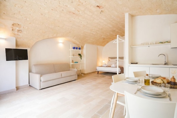 Un espacio moderno para vivir con un sofá, una mesa de comedor para dos personas y una zona de cocina.