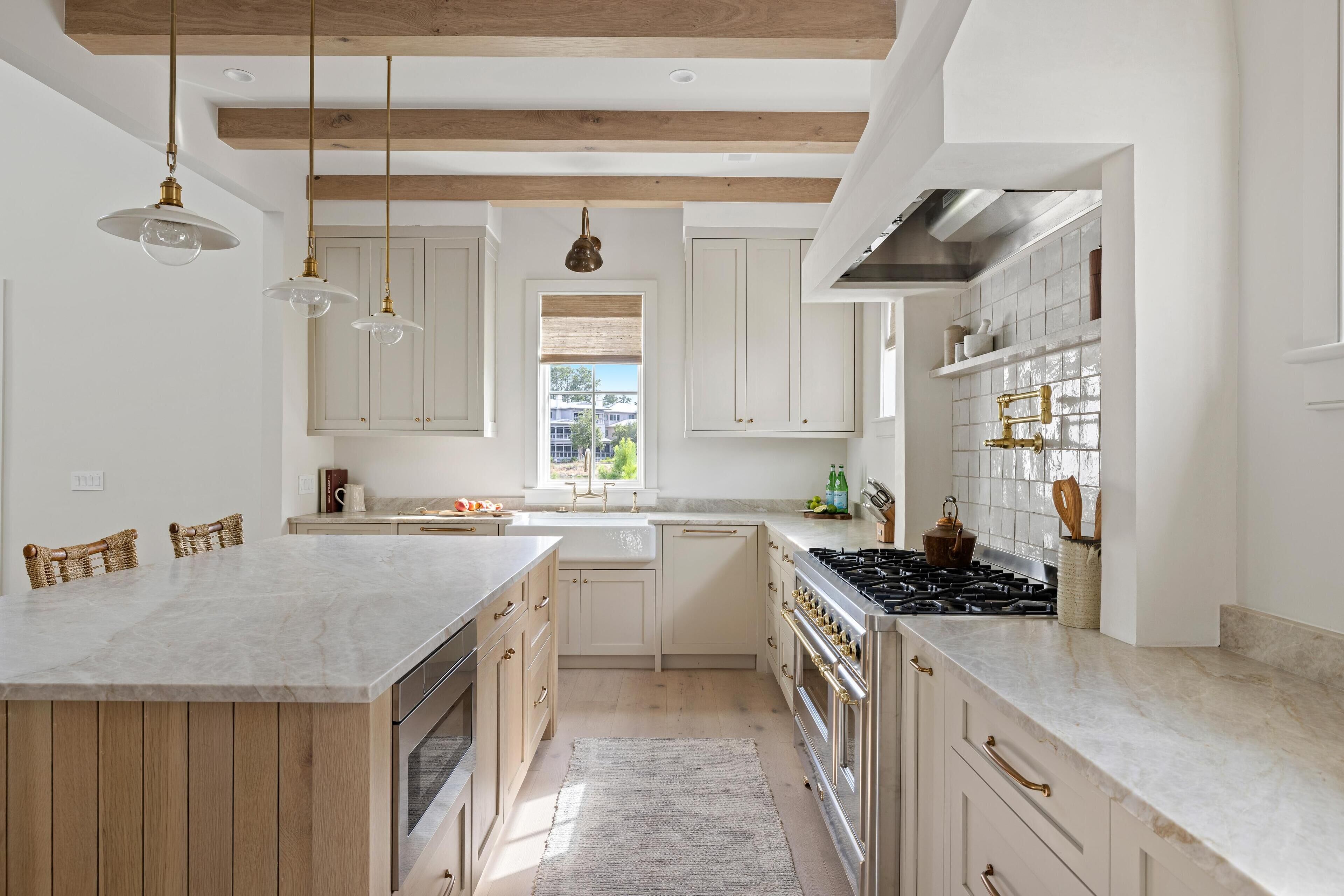 Een moderne keuken met houten balken, witte kastjes, een groot eiland en roestvrijstalen apparatuur.