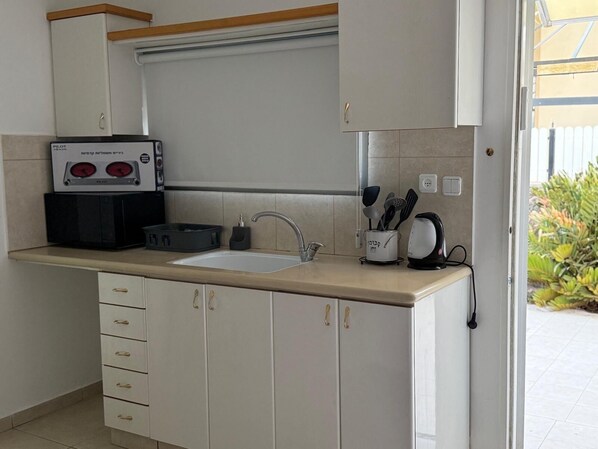 A kitchen with a sink, cabinets, and a coffee maker.