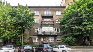 A multi-story building with a central entrance, balconies, and parked cars in front. - ShortStayPoland Józefitów C4 (Kraków)