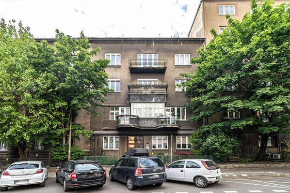 A multi-story building with a central entrance, balconies, and parked cars in front. - ShortStayPoland Józefitów C4 (Kraków)