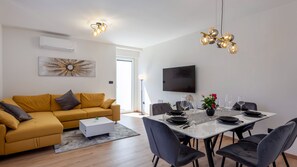 Un salon moderne comprenant un canapé, une table à manger, des chaises et un téléviseur à écran plat.