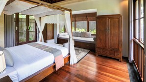 A bedroom with a four-poster bed, a wooden cabinet, and a seating area with a bench and cushions. - Specious  three bedrooms villa in beautiful Jimbaran with private pool (Bali)