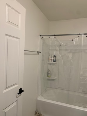 Une salle de bain avec une baignoire, un rideau de douche et une porte.