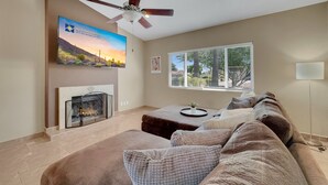 A living room with a fireplace, a ceiling fan, a large window with blinds, and a sofa. - Yorkshire Glendale (Glendale)