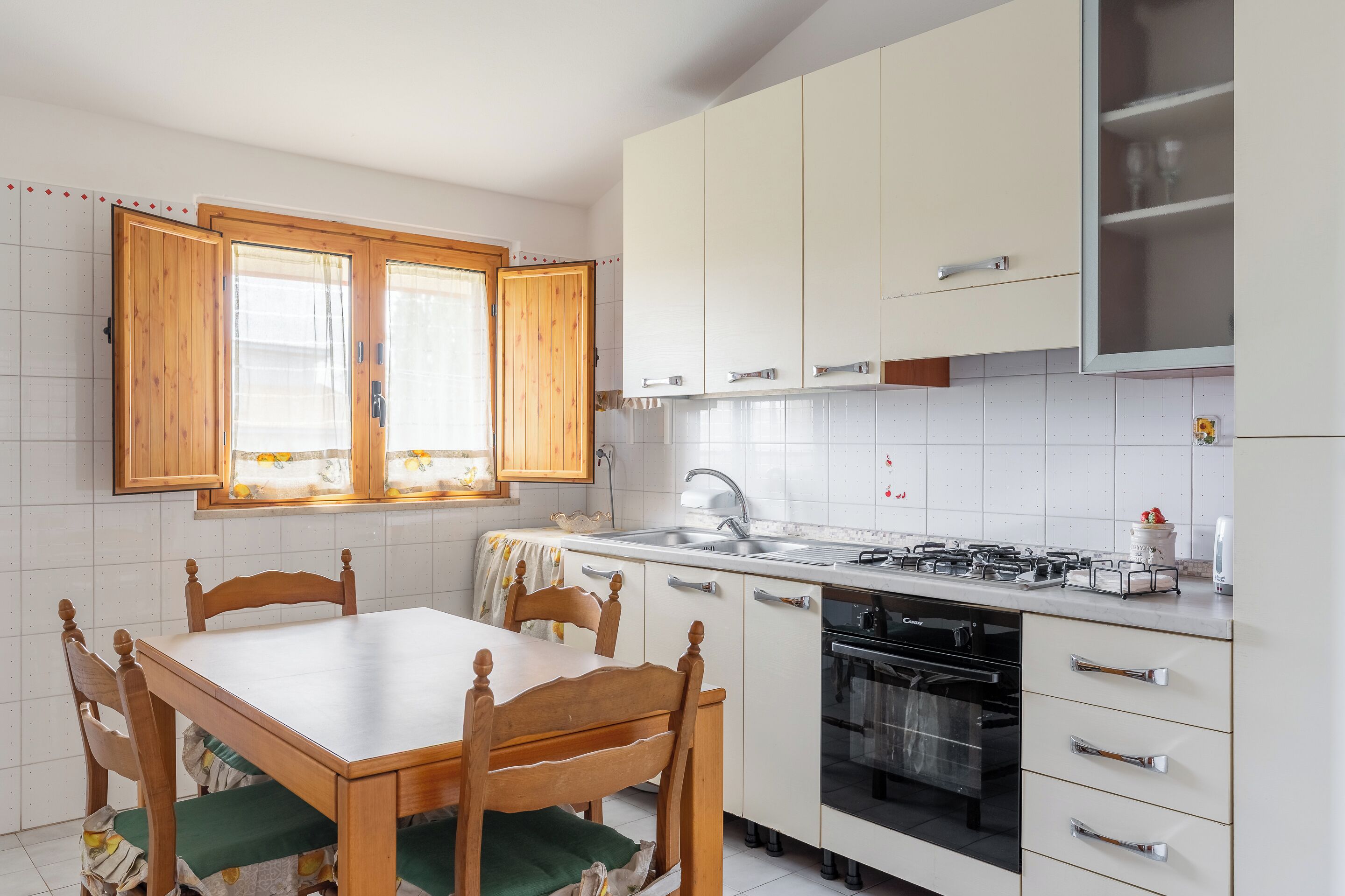 Una cocina con armarios de madera, encimera blanca, estufa y fregadero.