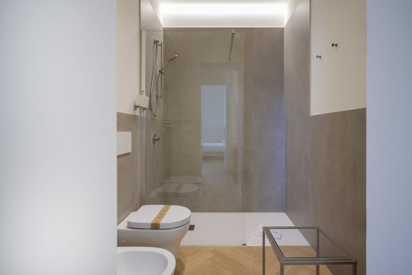 Une salle de bain moderne avec une douche à parois de verre, des toilettes et une petite table.