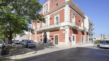 A two-story building with a red and white facade, a balcony on the second floor, and a gated entrance.