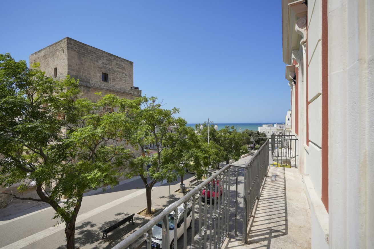 Un balcone con vista su un edificio storico e sul mare.