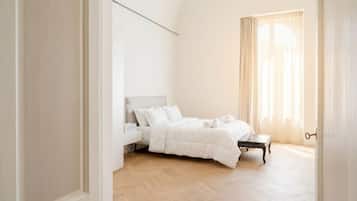 Ein Schlafzimmer mit einem Bett, einem Nachttisch, einem Fenster mit Vorhängen und einem Holzboden.