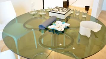 A round glass table with a book, glasses, and a rolled-up mat.